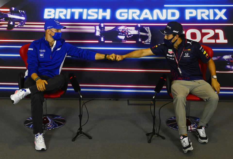 FILE - In this July 15, 2021 file photo, Haas driver Mick Schumacher of Germany, left, and Red Bull driver Sergio Perez of Mexico greet each other with a fist bump as they attend a media conference at the Silverstone circuit, Silverstone, England. As workers return to the office, friends reunite and more church services shift from Zoom to in person, this exact question is befuddling growing numbers of people: to shake or not to shake. (Mark Sutton, Pool Photo via AP, File)