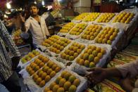 In this Tuesday, May 6, 2014 photo, an Indian vendor talks to a customer as Alphonso mangoes are displayed at a whole sale market in Mumbai, India. Starting May 1, the EU banned imports of Indian mangoes including the Alphonso, considered the king of all the mango varieties available in South Asia. The ban was implemented because a large number of shipments were contaminated with fruit flies. (AP Photo/Rajanish Kakade)