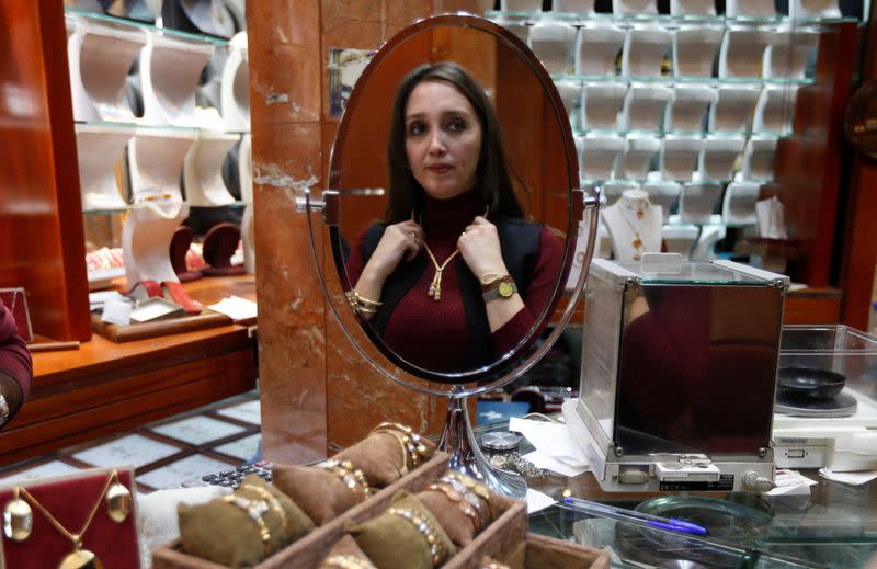 A woman is reflected in a mirror as she tries on a necklace at a jewellery shop in Beirut