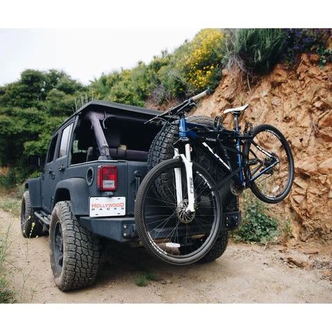 bike mounted to spare tire of jeep on dirt road