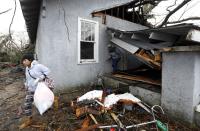 Nora Martinez carries her possessions out of a house she shared with two other people after a tornado destroyed the residence, Saturday, Jan. 21, 2017 in Hattiesburg, Miss. The tornado was part of a wall of stormy weather traveling across the region, bringing with it rain and unstable conditions.(AP Photo/Rogelio V. Solis)