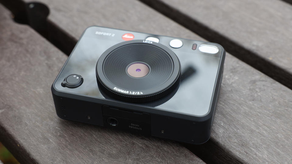 Bottom of a Leica Sofort 2 hybrid camera on a slatted wooden table