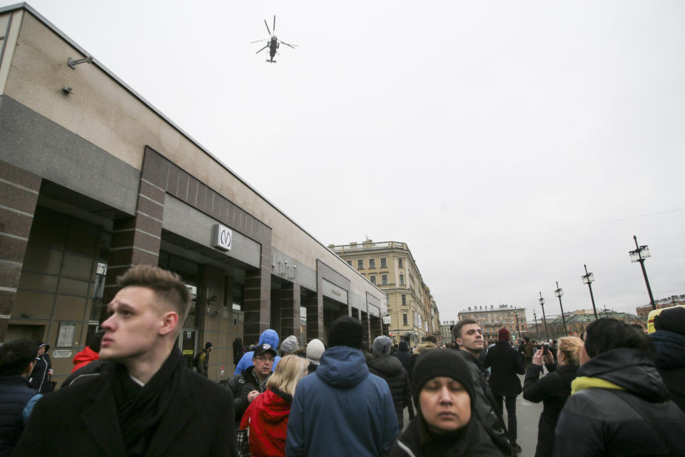 People walk past the entrance of Spasskaya subway station after a explosion in St.Petersburg's subway, Russia, Monday, April 3, 2017. The subway in the Russian city of St. Petersburg is reporting that there are fatalities and several people have been injured in an explosion on a subway train. (AP Photo/Evgenii Kurskov)