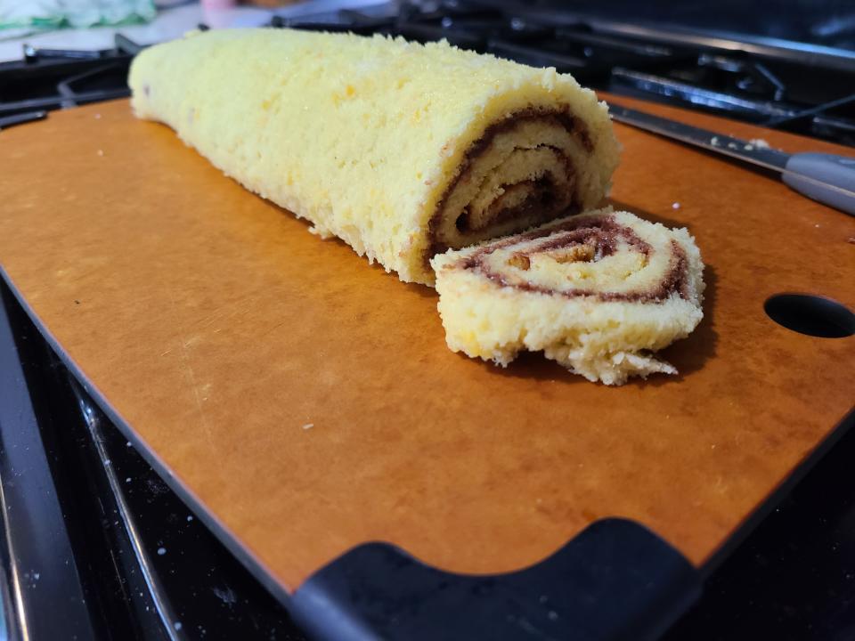 An unfrosted yule log cake with a piece cut from it.