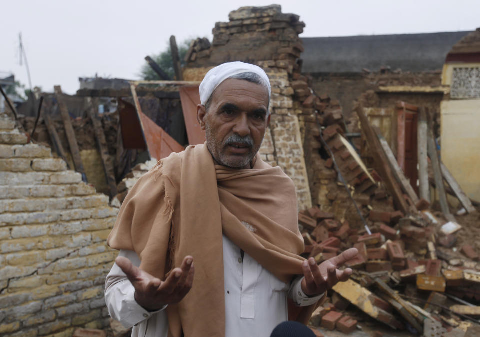 An injured earthquake survivor describes his story next to his damage house caused by a powerful earthquake struck Sahang Kikri village near Mirpur, in northeast Pakistan, Wednesday, Sept. 25, 2019. A powerful earthquake struck northeast Pakistan Tuesday, badly damaging scores of home and shops and killing some people and injured over 700, officials, said. (AP Photo/Anjum Naveed)