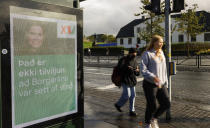 People walk past an election poster from the Left Green Party, showing Prime Minister Katrin Jakobsdottir and saying "It isn't coincidence that the City Lane was launched" in Reykjavik, Iceland, Wednesday, Sept. 22, 2021. Climate change is top of the agenda when voters in Iceland head to the polls for general elections on Saturday, following an exceptionally warm summer and an election campaign defined by a wide-reaching debate on global warming. Polls suggest Prime Minister Katrin Jakobsdottir's Left Green Party could face a poor outcome, ending the current coalition. (AP Photo/Brynjar Gunnarsson)