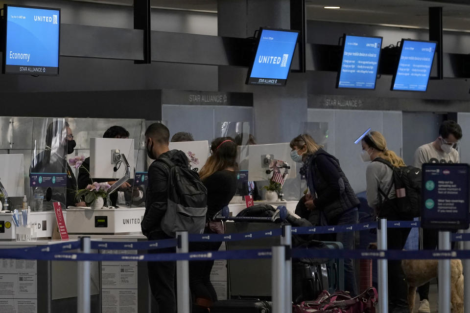 Travelers wearing masks check in at United desks at San Francisco International Airport during the coronavirus outbreak in San Francisco, Tuesday, Nov. 24, 2020. (AP Photo/Jeff Chiu)