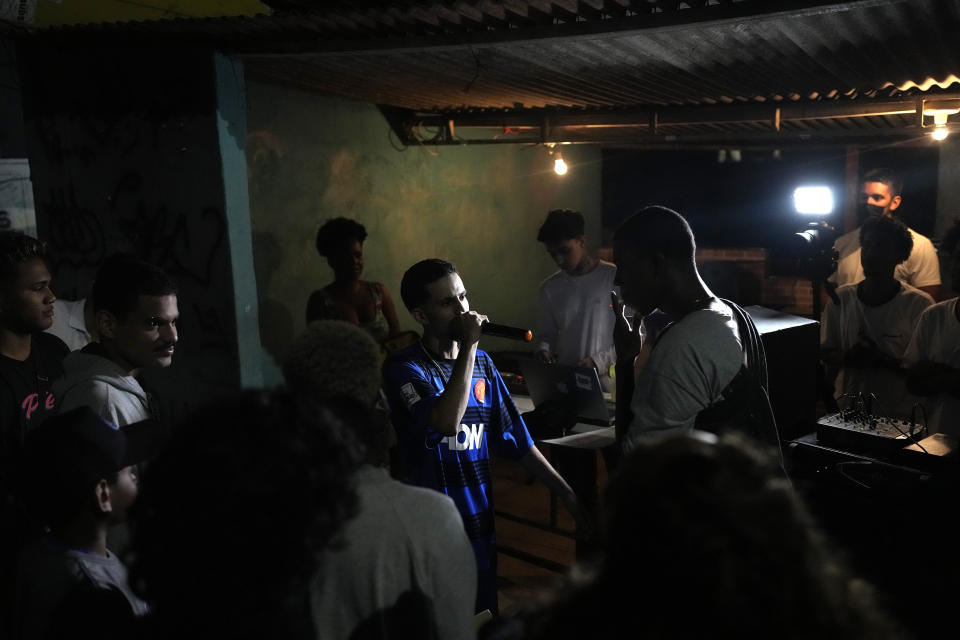 Rappers battle during the Gas Battle competition outside a bar in the City of God favela in the City of God favela of Rio de Janeiro, Brazil, late Wednesday, Nov. 10, 2021. Rap artists in the favela are starting to compete again since the COVID-19 pandemic curtailed public gatherings, presenting local residents with a show in a sign of a return to normalcy for music lovers. (AP Photo/Silvia Izquierdo)