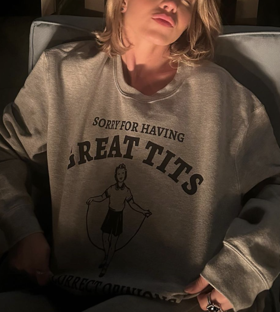 Person in a graphic sweatshirt with text "SORRY FOR HAVING GREAT TITS" and a cartoon figure