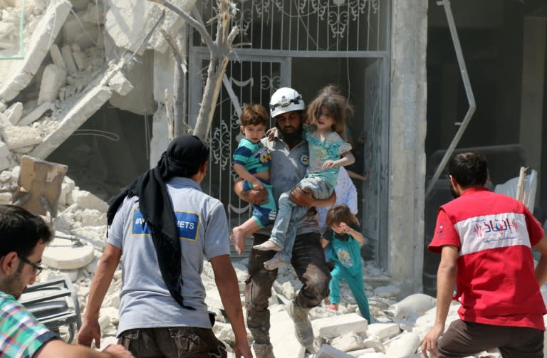 A Syrian rescue worker carries children in the Maadi district of eastern Aleppo after regime aircrafts reportedly dropped barrel bombs