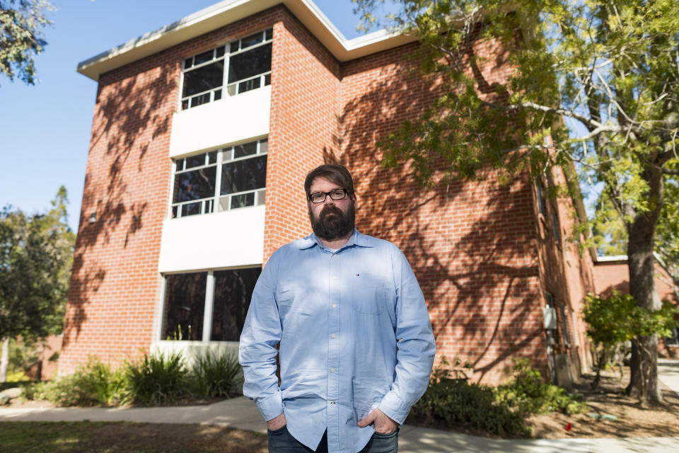 Chris Lambert, a musician and recording engineer, poses Thursday, April 15, 2021, in front of Muir Hall dormitory at California Polytechnic University in San Luis Obispo, Calif. Lambert started a podcast to document the 1996 disappearance of Kristin Smart, who was a college student at Cal Poly and lived in Muir Hall when she disappeared. On Tuesday, April 13, 2021, the San Luis Obispo County sheriff announced arrests in the 25-year-old case, crediting Lambert with helping bring in witnesses that propelled the case forward. (AP Photo/Nic Coury)