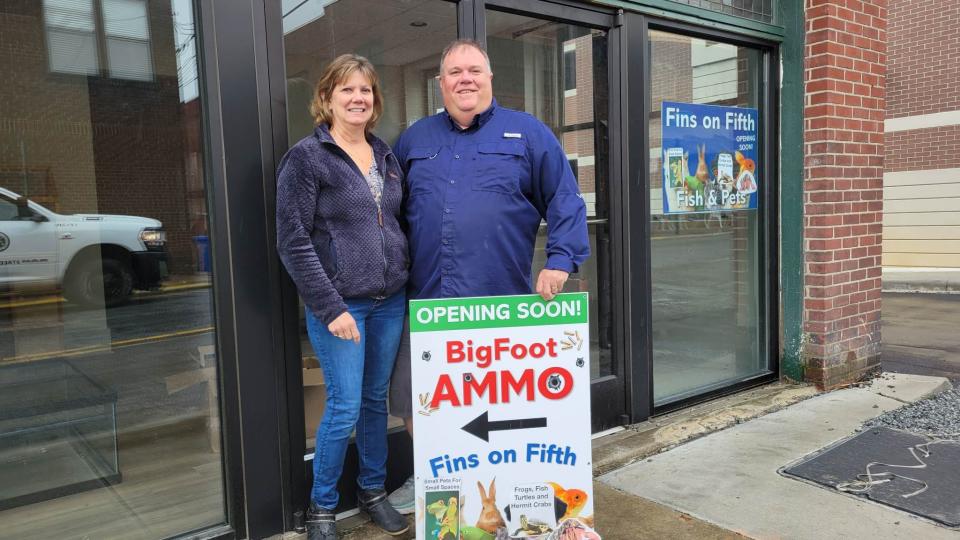 Daryl and Lisa Waldrop pose in front of the Fins on Fifth storefront on Fifth Avenue in downtown Hendersonville. Located beside the store is another store owned by the Waldrops called BigFoot Ammo and More.