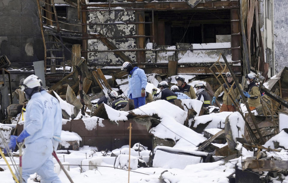 Firefighters search the snow-covered rubble at a marketplace after a large fire in the earthquake-hit city, Wajima, Ishikawa prefecture, Monday, Jan. 8, 2024. Thousands of people made homeless overnight are living in weariness and uncertainty on the western coast of Japan a week after powerful earthquakes hit the region. (Kyodo News via AP)