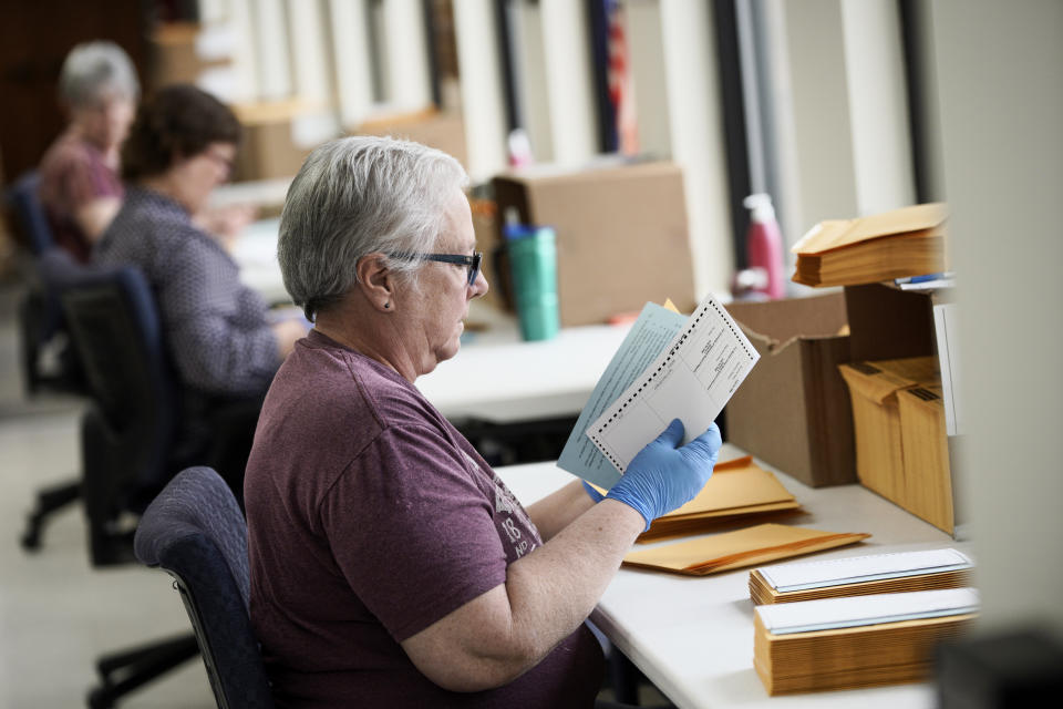 In this April 14, 2020 photo, Pam Fleming and fellow workers stuff ballots and instructions into mail-in envelopes at the Lancaster County Election Committee offices in Lincoln, Neb. Officials in Nebraska are forging ahead with plans for the state’s May 12 primary despite calls from Democrats to only offer voting by mail and concerns from public health officials that in-person voting will help the coronavirus spread. (AP Photo/Nati Harnik)