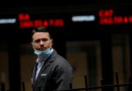 FILE PHOTO: FILE PHOTO: A trader walks past a digital stock price display outside the New York Stock Exchange in New York