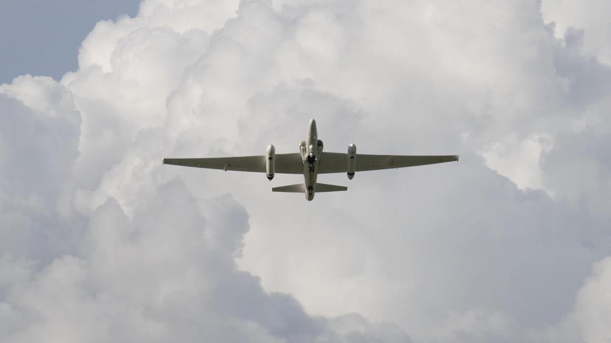  a plane with a large wingspan flies under cloudy skies 