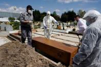 A member of the Islamic community, funeral workers, relatives and friends of a person who died of coronavirus disease (COVID-19) put the coffin in the grave at the Spanish muslim military cemetery, in Grinon