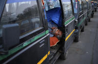 In this Monday, March 24, 2014 photo, an Indian taxi driver sleeps inside his traditional black-and-yellow licensed cab as he waits for customers in New Delhi, India. Most licensed taxis are banned from having air conditioning under an archaic municipal rule, leaving passengers suffering with rolled-down windows in suffocating heat and noxious pollution. Taxi-hailing smartphone app Uber is making a big push into Asia with the company starting operations in 18 cities in Asia and the South Pacific including Seoul, Shanghai, Bangkok, Hong Kong and five Indian cities in the last year. (AP Photo/Saurabh Das)