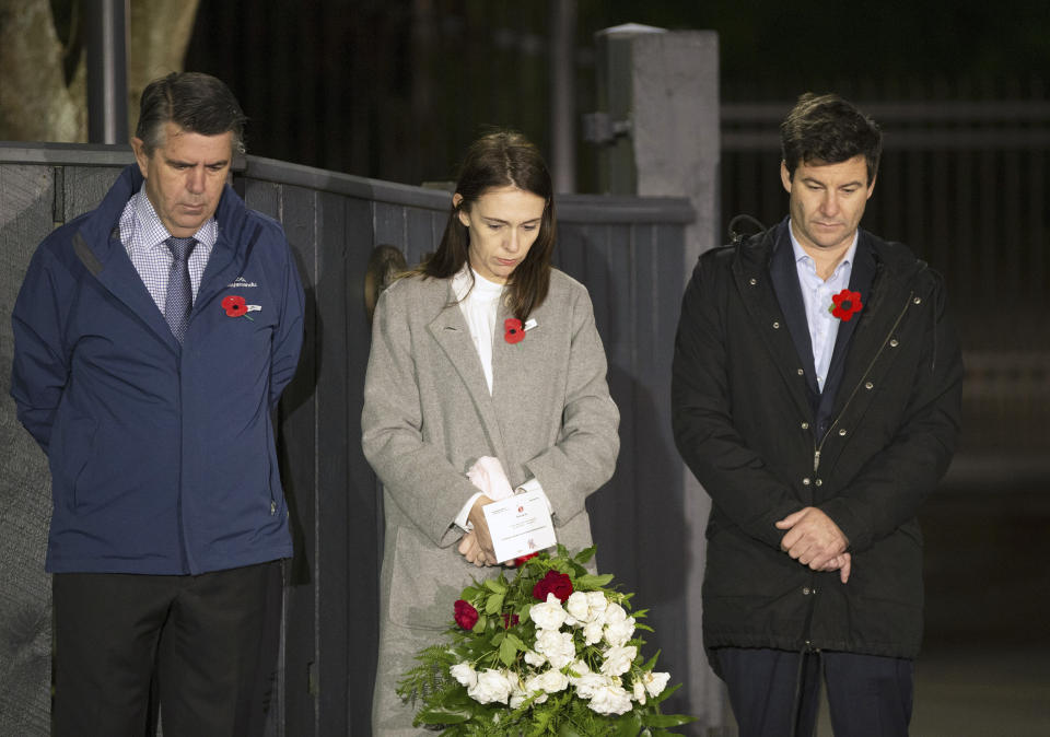New Zealand Prime Minister Jacinda Ardern stands at dawn on the driveway of Premier House with her father Ross Ardern, left, and partner Clarke Gayford to commemorate Anzac Day in Wellington, New Zealand, Saturday, April 25, 2020. Many New Zealanders participated in the "Stand At Dawn" initiative to commemorate Anzac Day after the traditional services were canceled due to COVID-19. (Ross Giblin/Dominion Post, Pool photo via AP)