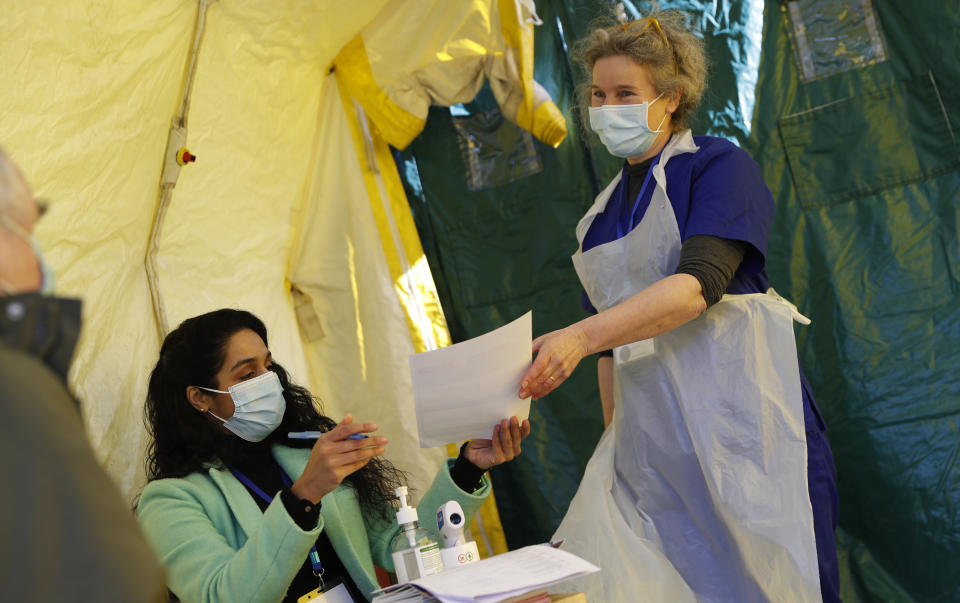 Dr Tamara Joffe, right takes a completed vaccine form from Dr Sabeena Pheerunggee as they prepare to give the AstraZeneca vaccine to a patient during the pilot project of pop up vaccination drive 'Vaxi Taxi' in Kilburn, London, Sunday, Feb. 28, 2021. The pilot scheme, funded by the Covid Crisis Rescue Foundation, aims to help ferry supplies and patients to temporary clinics set up in faith and community centres across the capital. People don’t even need to leave the backseat if they didn’t want to in order to receive their inoculation. (AP Photo/Alastair Grant)