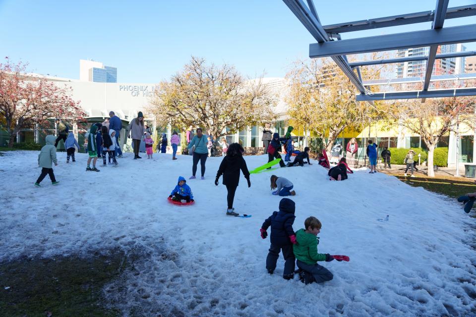 Kids and parents play in the snow outside the Arizona Science Center during the Science Center's 12th annual Snow Week on Dec. 28, 2023, in Phoenix, Ariz.