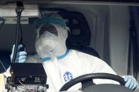 A paramedic wearing protective gear drives an ambulance in central Athens, Tuesday, Oct. 20, 2020. Greece has been experiencing a resurgence of the coronavirus, with the number of new daily cases, most in the Greek capital, often topping 400, and both deaths and the number of those in intensive care units rising. (AP Photo/Thanassis Stavrakis)