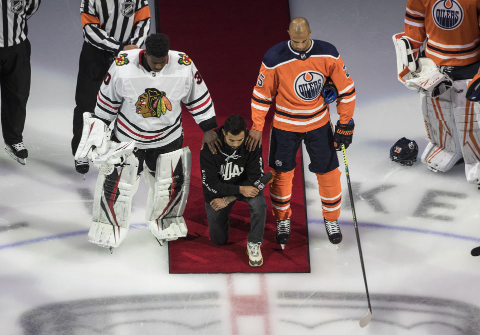 FILE - In this Aug. 1, 2020, file photo, Minnesota Wild's Matt Dumba takes a knee during the national anthem flanked by Edmonton Oilers' Darnell Nurse, right, and Chicago Blackhawks' Malcolm Subban before an NHL hockey Stanley Cup playoff game in Edmonton, Alberta. Dumba gave a speech on behalf of the NHL and Hockey Diversity Alliance before one of the first games of the NHL’s restart between Edmonton and Chicago, which he was not playing in. (Jason Franson/The Canadian Press via AP, File)