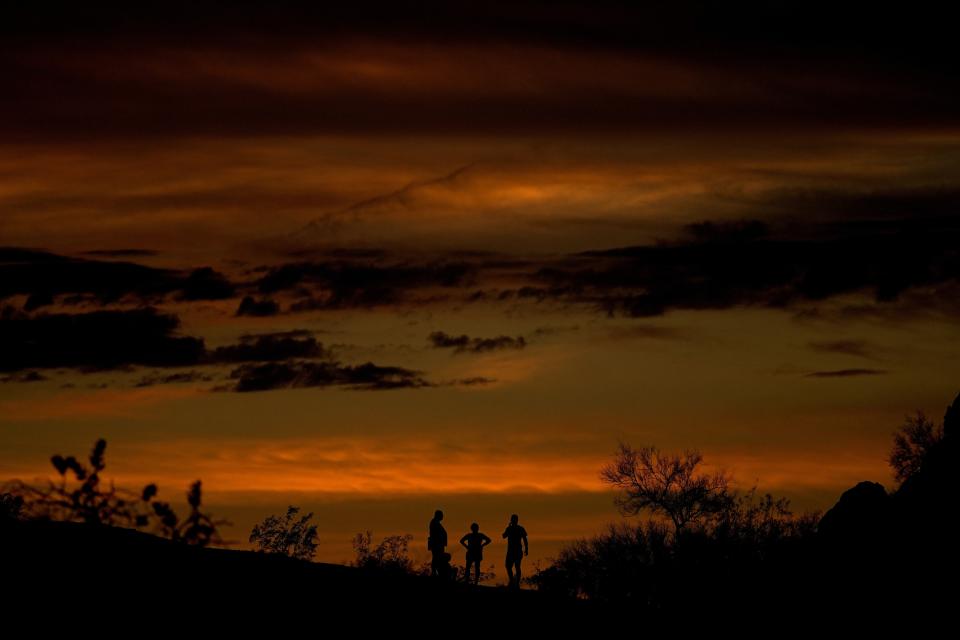 FILE - People watch the stand atop a rock formation to watch sunset, July 30, 2023, in Phoenix. At about summer's halfway point, the record-breaking heat and weather extremes are both unprecedented and unsurprising, hellish yet boring in some ways, scientists say. (AP Photo/Matt York, File)