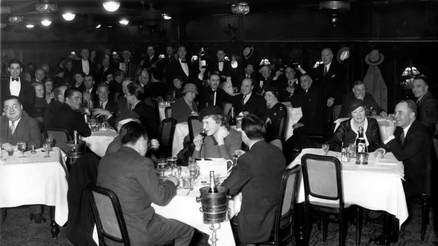 Dozens of people sit and enjoy drinks inside of a busy restaurant.