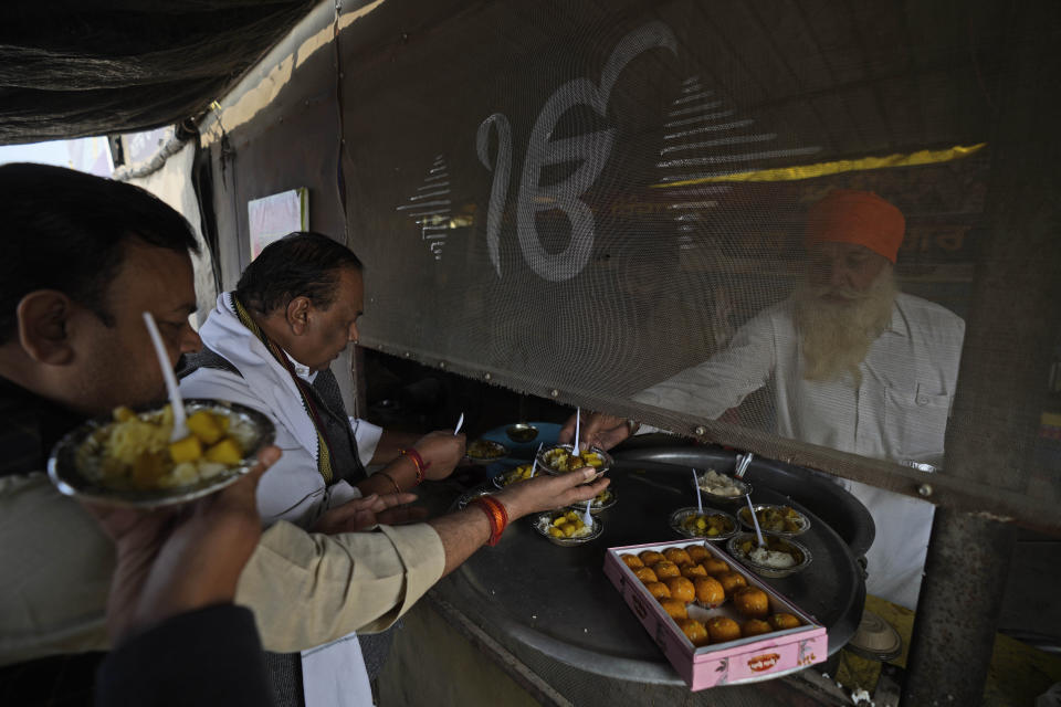 Farmers distribute sweets to celebrate news of the repeal of farm laws they were protesting against, in Singhu, on the outskirts of New Delhi, India, Friday, Nov. 19, 2021. In a surprise announcement, India's Prime Minister Narendra Modi said Friday his government will withdraw the controversial agriculture laws that prompted yearlong protests from tens of thousands of farmers and posed a significant political challenge to his administration. (AP Photo/Manish Swarup)