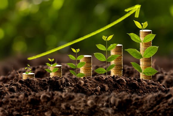 Stacks of coins and plants growing in soil, with an drawn arrow to illustrate growth.