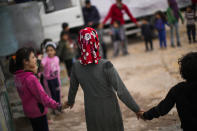 Syrian children hold hangs as they wait for a delivery of food and toys in Taybe refugee orphanage camp for displaced people run by the Turkish Red Crescent in Sarmada district, on the outskirts north of Idlib, Syria, Thursday, Nov. 25, 2021. (AP Photo/Francisco Seco)