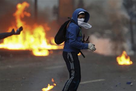 An anti-government protester turns after throwing a molotov at police during clashes in Caracas March 15, 2014. REUTERS/Jorge Silva