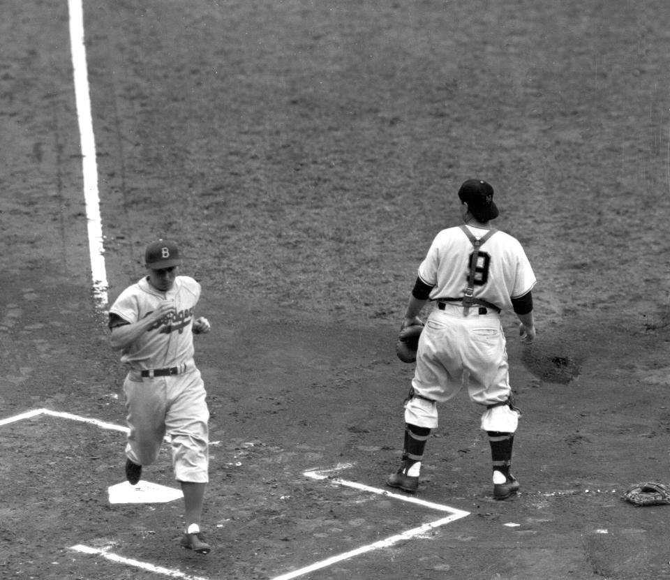 Brooklyn Dodgers shortstop Pee Wee Reese crosses home plate behind New York Giants catcher Wes Westrum.