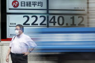 A man stands near an electronic stock board showing Japan's Nikkei 225 index at a securities firm as a track passes by in Tokyo Friday, July 3, 2020. Markets advanced in Asia on Friday following a Wall Street rally driven by strong jobs data. (AP Photo/Eugene Hoshiko)