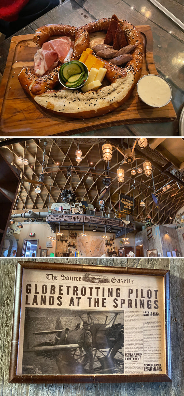 a plate of a large pretzel with cheese slices and old newspapers clippings on the wall