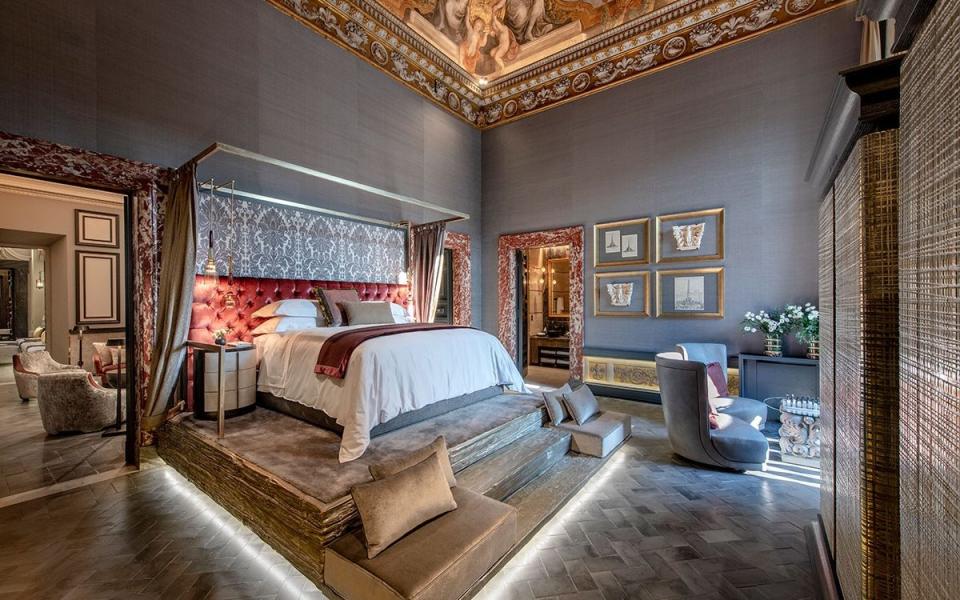 bed on raised platform with red leather headboard, high ceilings with motifs - Giovanni De Sandre 