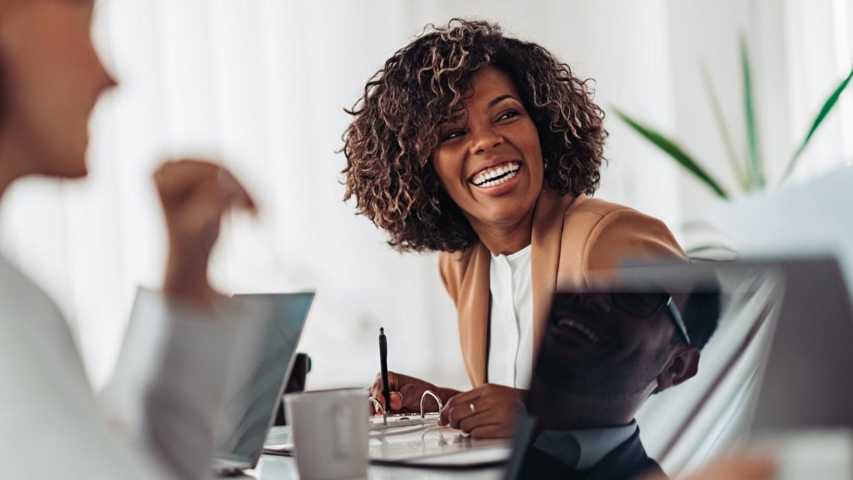 Portrait of cheerful african american businesswoman discussing and smiling at the meeting with colleagues.