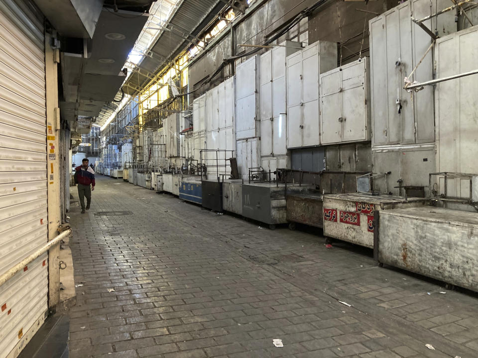 A man walks through closed shops of Tehran's Grand Bazaar, Iran, Tuesday, Nov. 15, 2022. Many shops at Grand Bazaar in Iran's capital city were closed Tuesday amid strike calls following the September death of a woman who was arrested by the country's morality police. (AP Photo/Vahid Salemi)