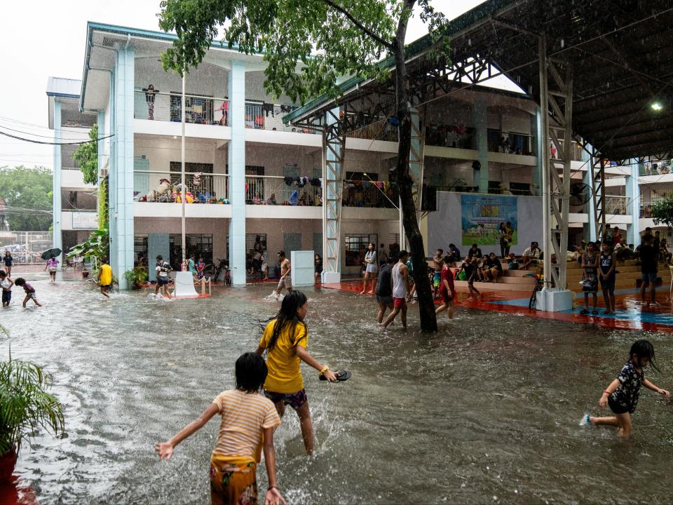 Children play amid flooding at a school temporarily converted into an evacuation centre in Manila (REUTERS)