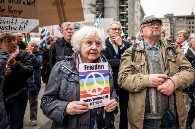Sabine Rosenbrock (L) holds a placard at Roncalliplatz during the Easter march under the motto 