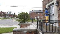 Robert Day knocks on a door before leaving a flyer on a home in Detroit, Tuesday, May 4, 2021. Officials are walking door-to-door to encourage residents of the majority Black city to get vaccinated against COVID-19 as the city's immunization rate lags well behind the rest of Michigan and the United States. (AP Photo/Paul Sancya)