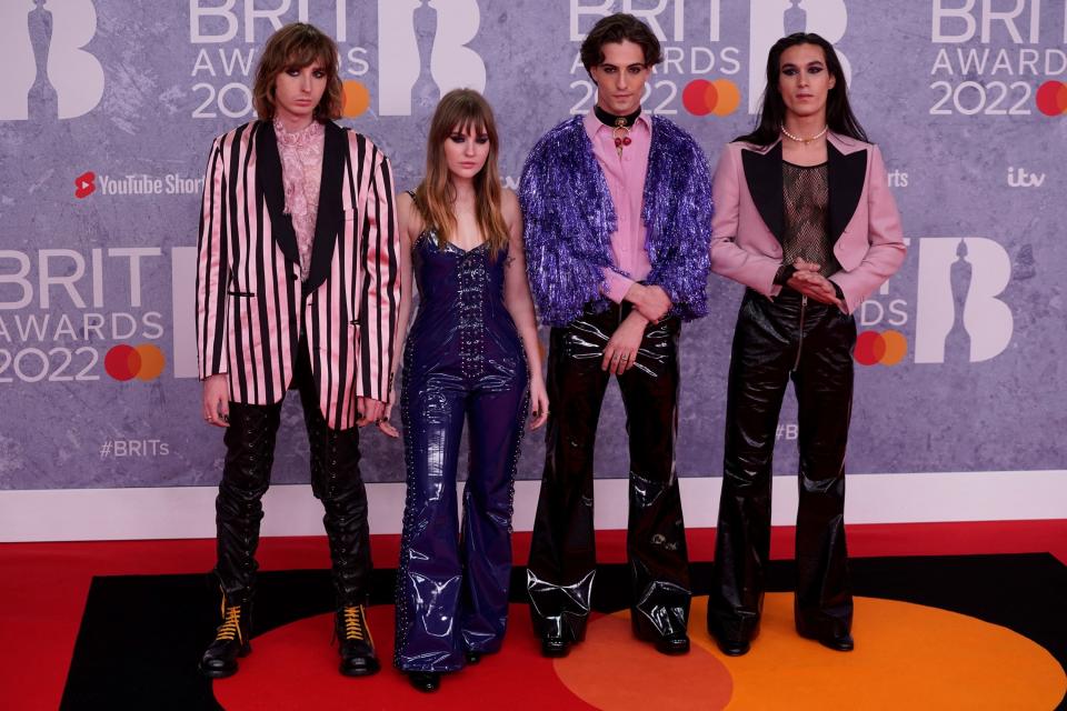 The band wears leather pants and coordinating pink and purple tops