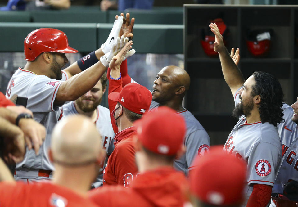 Los Angeles Angels Albert Pujols (5) is greeted in the dugout by Justin Upton, and Anthony Rendon after a solo home run in the third inning against the Texas Rangers during a baseball game on Monday, April 26, 2021, in Arlington, Texas. (AP Photo/Richard W. Rodriguez)