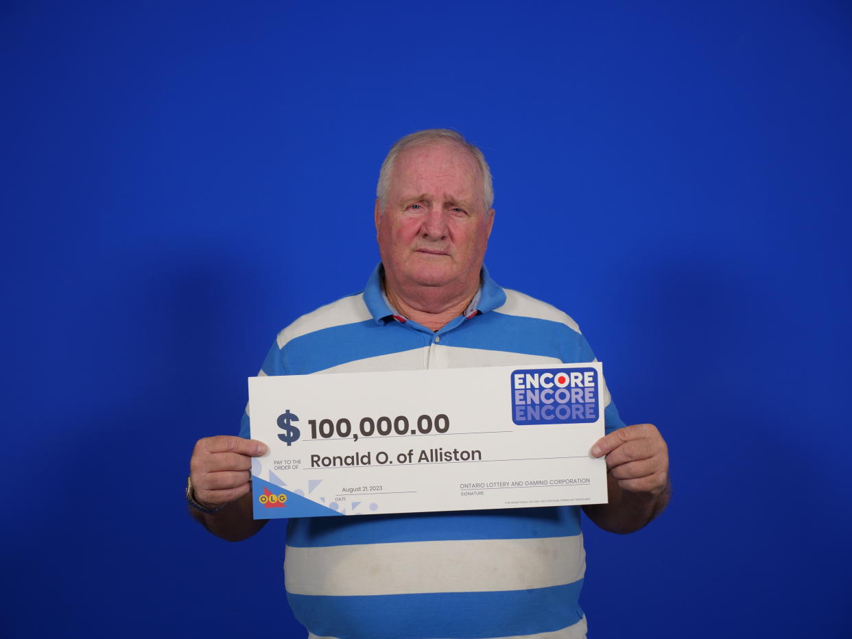 Man holding a lotto cheque worth $100,000
