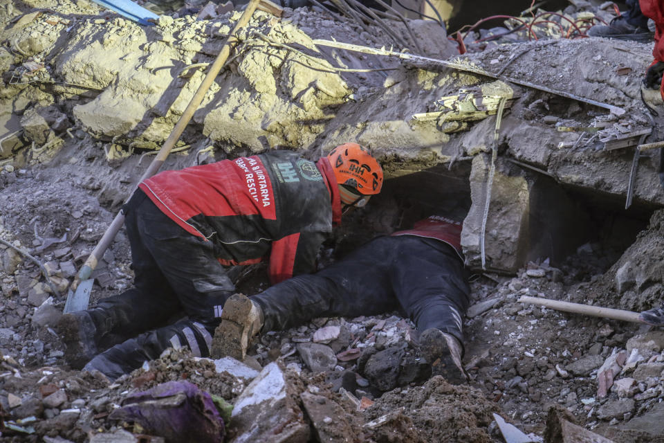 Rescue workers try to save people trapped under debris following a strong earthquake that destroyed several buildings on Friday, in Elazig, eastern Turkey, Sunday, Jan. 26, 2020. Rescue workers were continuing to search for people buried under the rubble of apartment blocks in Elazig and neighboring Malatya. Mosques, schools, sports halls and student dormitories were opened for hundreds who left their homes after the quake. (Ismail Coskun/IHA via AP)