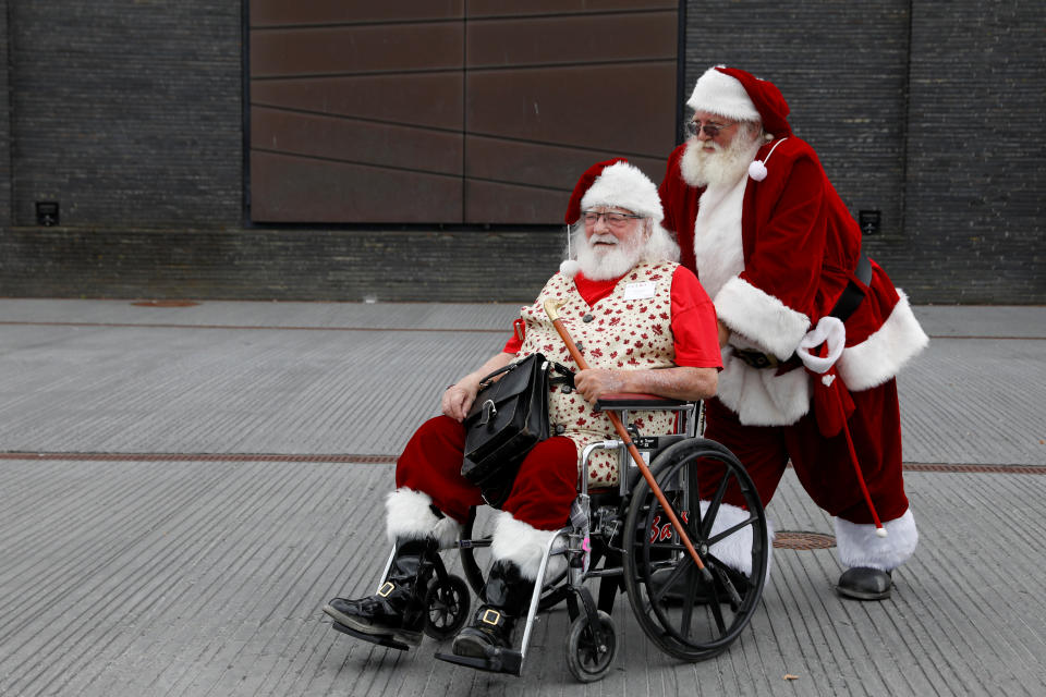 <p>A man helps another man in a wheelchair as they are dressed as Santa Claus during the World Santa Claus Congress, an annual event held every summer in Copenhagen, Denmark, July 23, 2018. (Photo: Andrew Kelly/Reuters) </p>