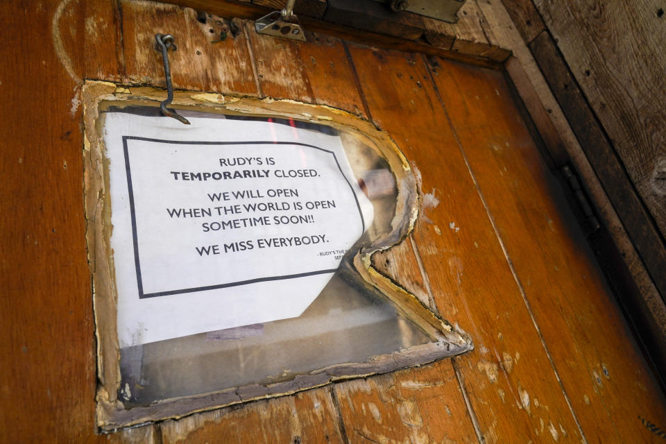 A sign at Rudy's Bar and Grill advises customers that they are temporarily closed, Sunday, Jan. 10, 2021, in the Hell's Kitchen neighborhood of New York. The boarded-up windows and For Rent signs are all over the place in Manhattan’s Hell’s Kitchen neighborhood. Nearby, the Broadway theaters are all dark. But the economic darkness brought on by the coronavirus pandemic has had a few bright spots. A couple of well-loved venues have gotten financial boosts, thanks to online fundraising campaigns and even a telethon. (AP Photo/Mary Altaffer)