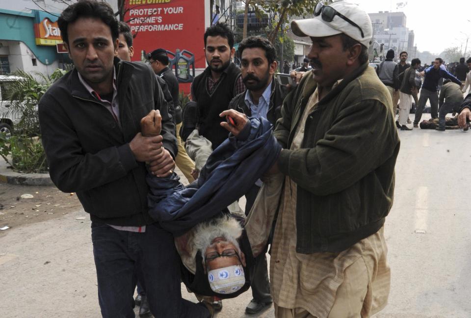 Residents carry an injured man from the site of an explosion outside the police headquarters, in Lahore