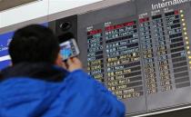 A man takes pictures of a flight information board displaying the Scheduled Time of Arrival (STA) of Malaysia Airlines flight MH370 at the Beijing Capital International Airport in Beijing, March 8, 2014. REUTERS/Kim Kyung-Hoon